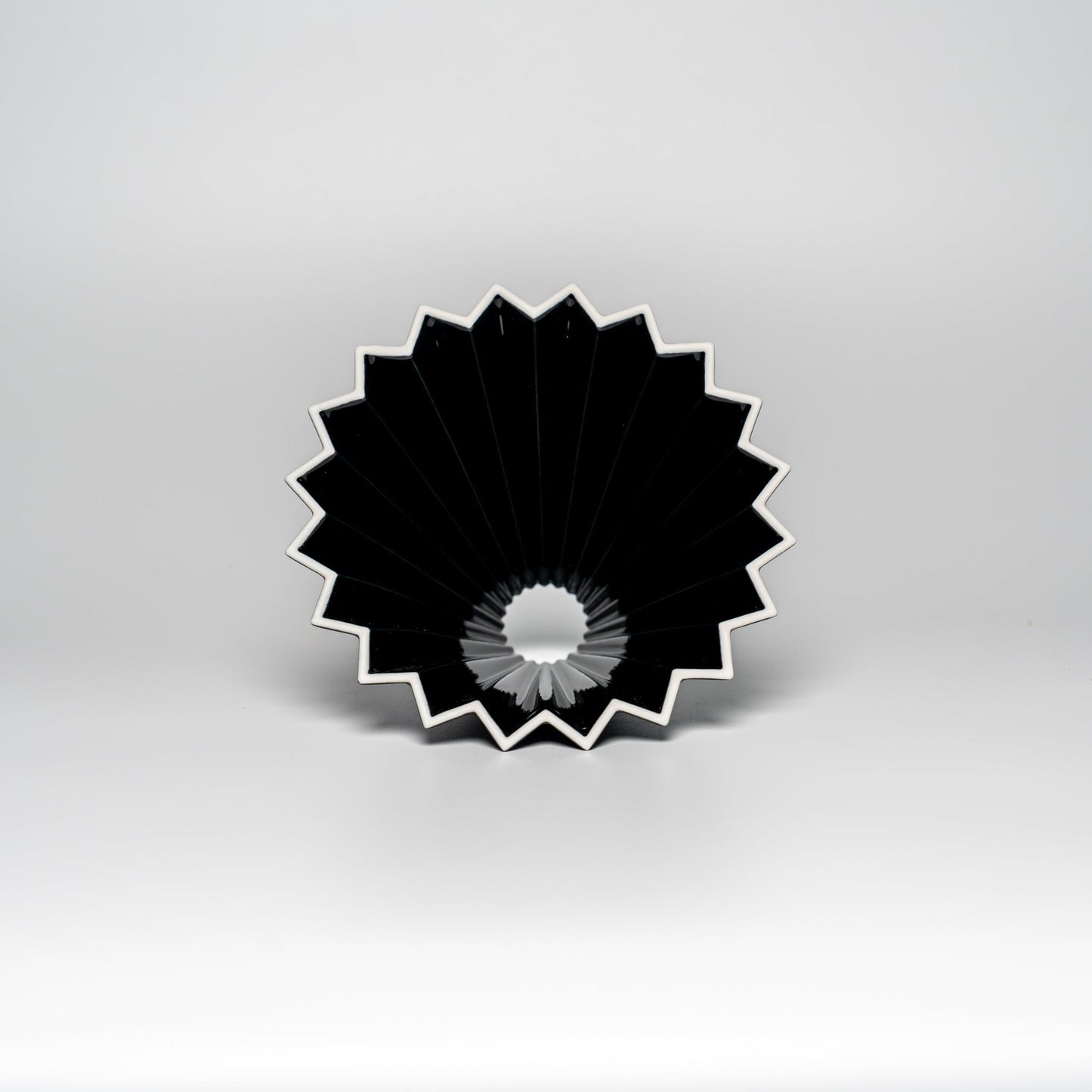 A black ORIGAMI coffee dripper on a white background