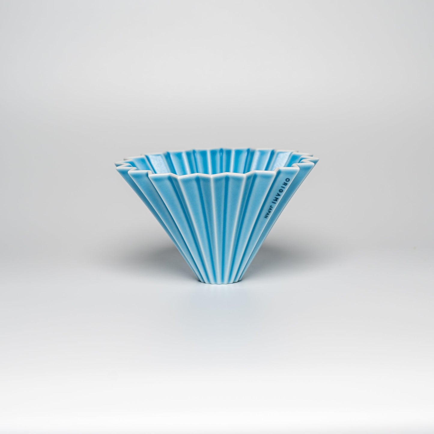 A bright blue ORIGAMI coffee dripper on a white background