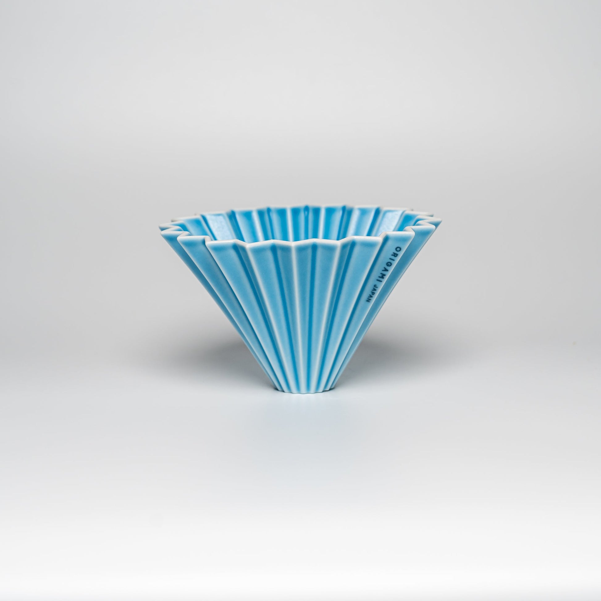 A bright blue ORIGAMI coffee dripper on a white background