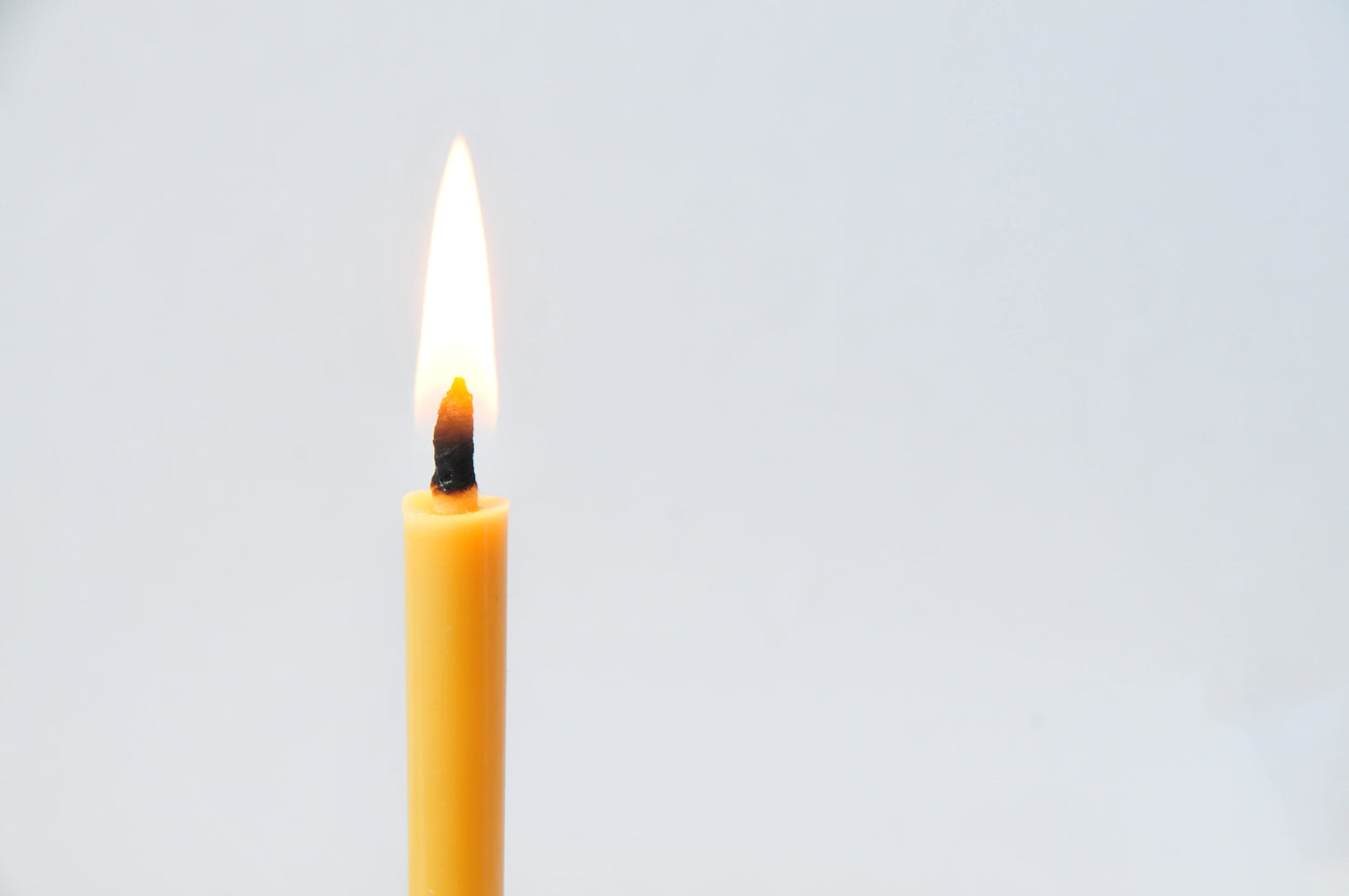 A lit rice wax candle on a white background