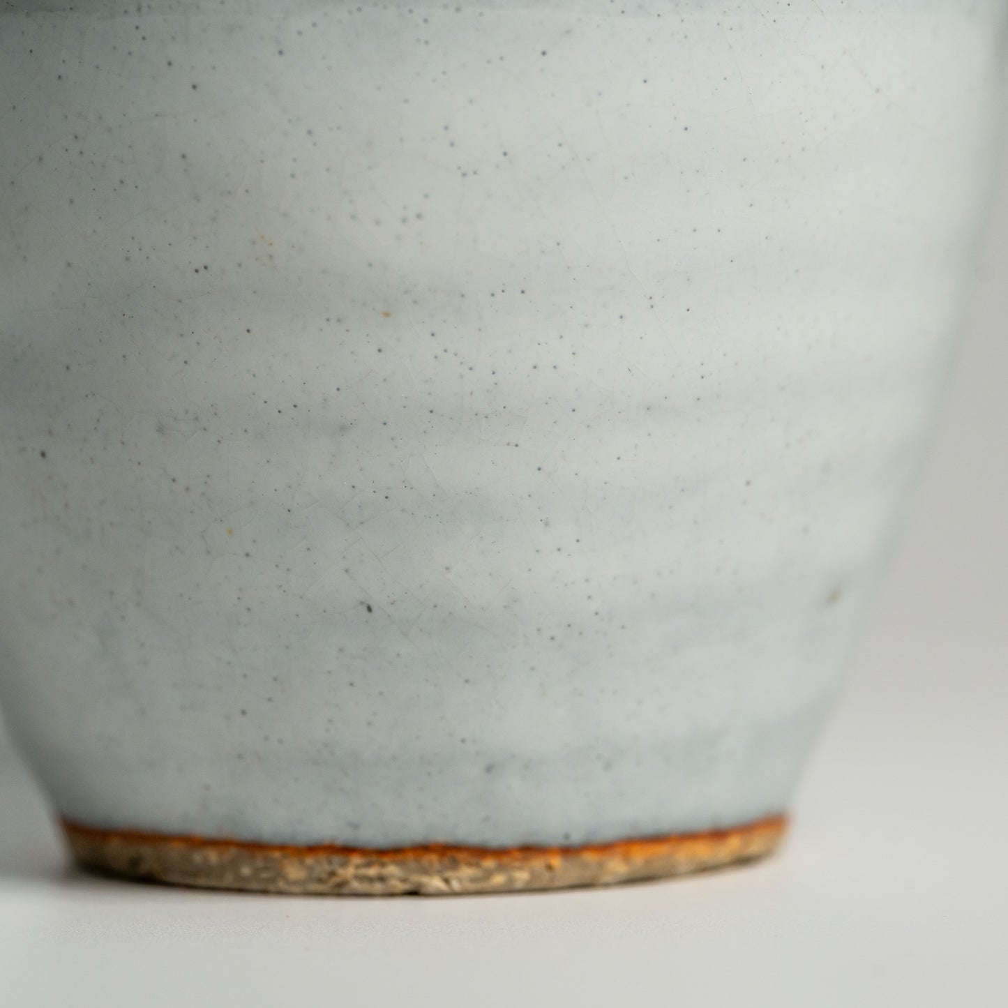 A close up of a white Hagi yaki teacup on a white background