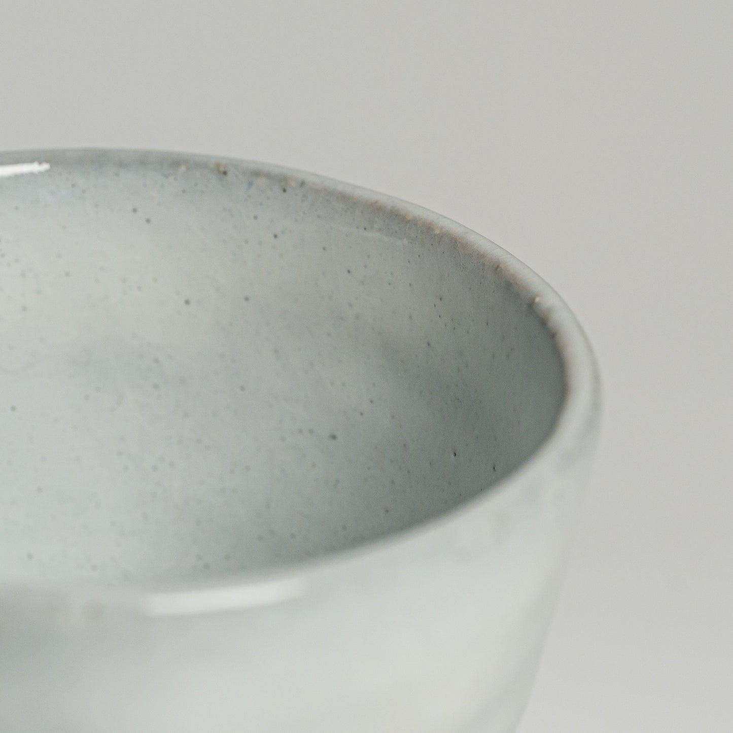 A close up of a white Hagi yaki teacup on a white background