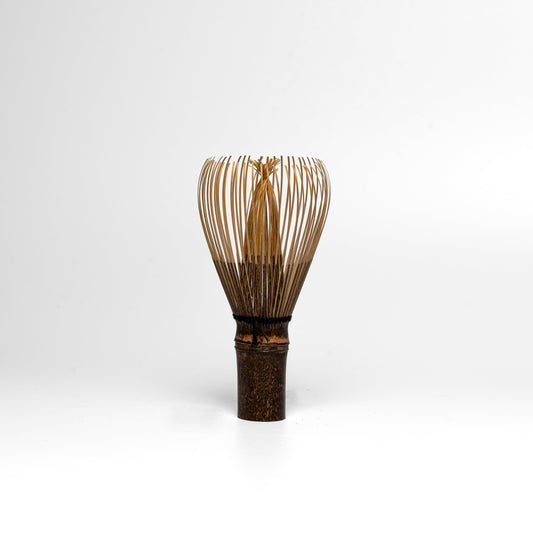 A black bamboo Takayama Chasen matcha whisk on a white background