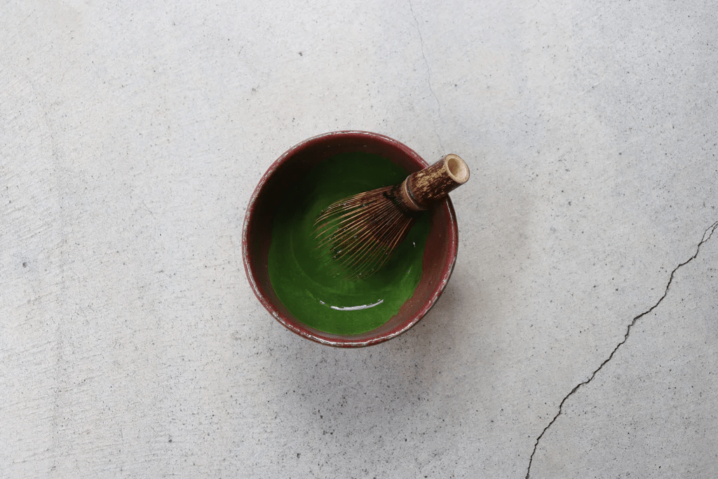 A Takayama chasen tea whisk in a bowl of thick matcha